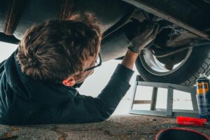 pexels photo 2244746 2244746 Mechanic skillfully repairing car undercarriage in outdoor setting with tools.